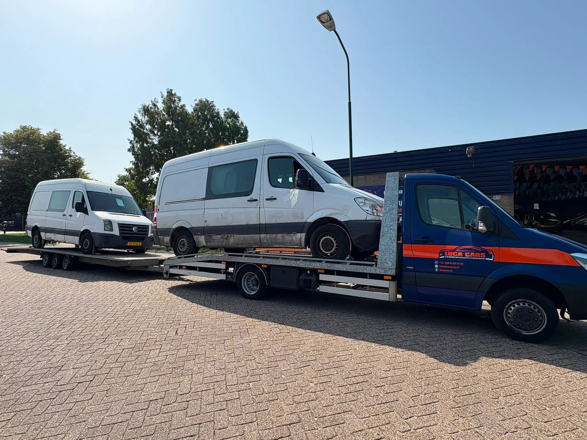 Twee bestelbussen vervoerd met een autotransporter en aanhanger